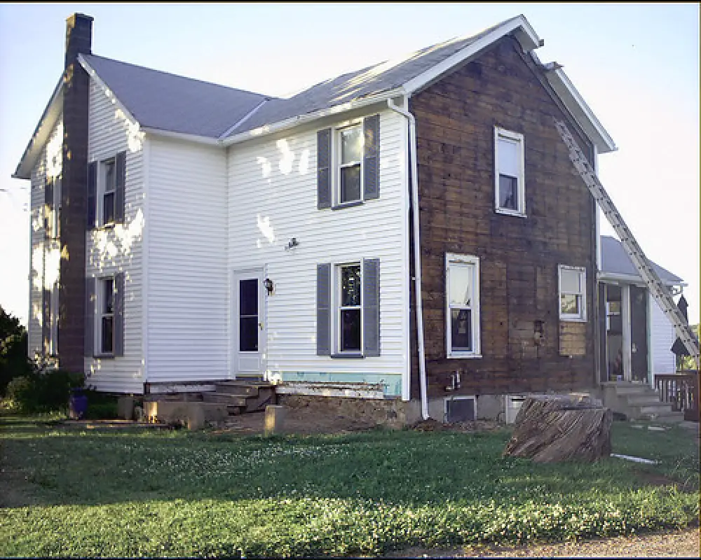 white house with wall of siding removed