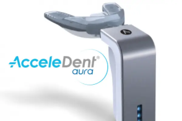 A dental device labeled AcceleDent aura with a mouthpiece and a metallic handle.