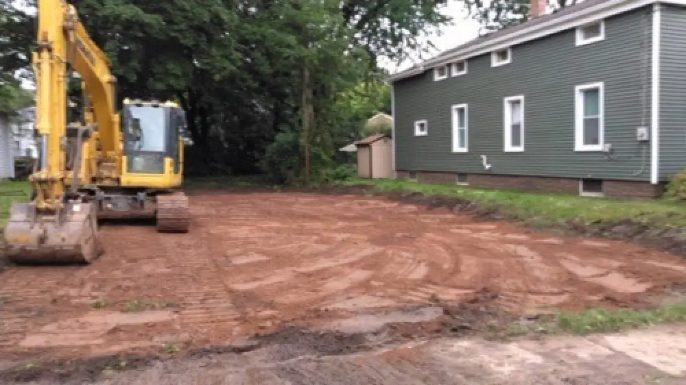 A backhoe on an empty piece of property after doing a demolition job.