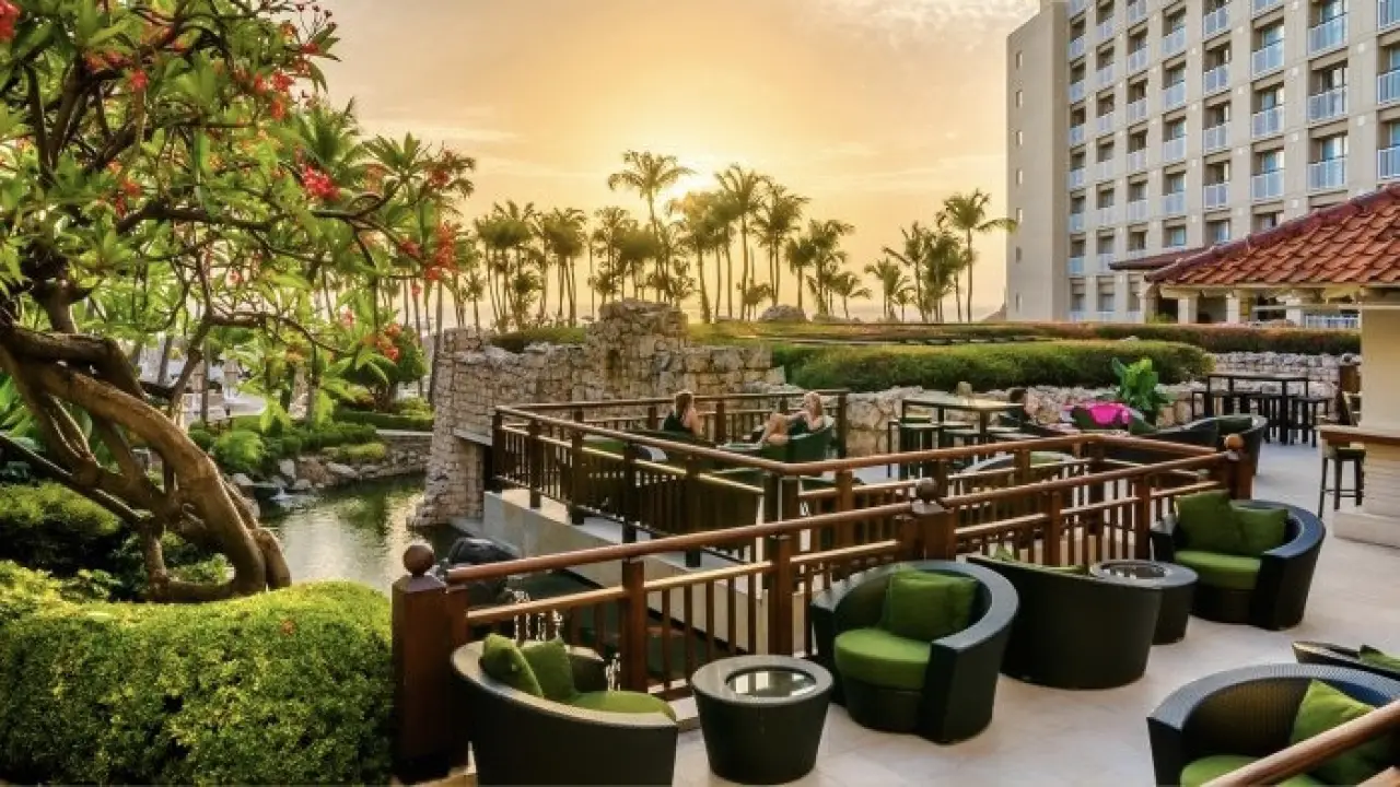 a pool with chairs and trees by it and buildings in the background