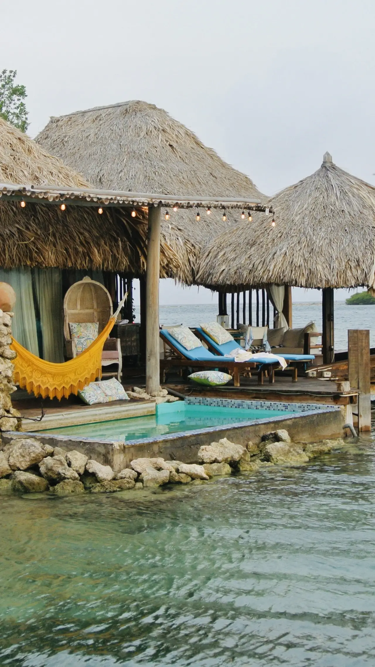 a pool with umbrellas and chairs by a beach