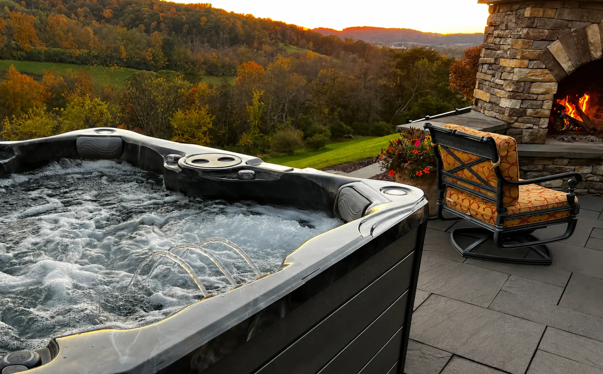 PDC Spas hot tub on a stone patio overlooking autumn hills at sunset