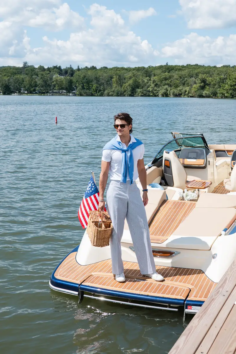 Man in custom seersucker trousers by Adrian Jules aboard a classic wooden boat on Canandaigua Lake