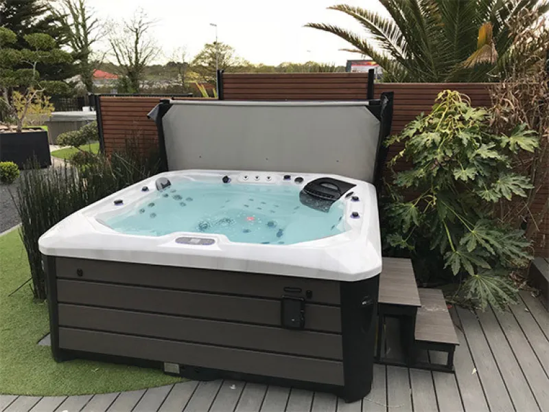 PDC Spas hot tub with cover lifter on a backyard patio