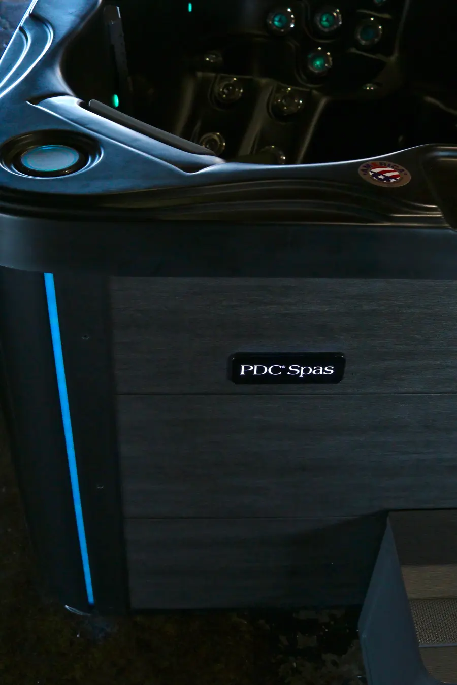 Midnight Series gray cabinet with PDC Spas badge and blue accent light